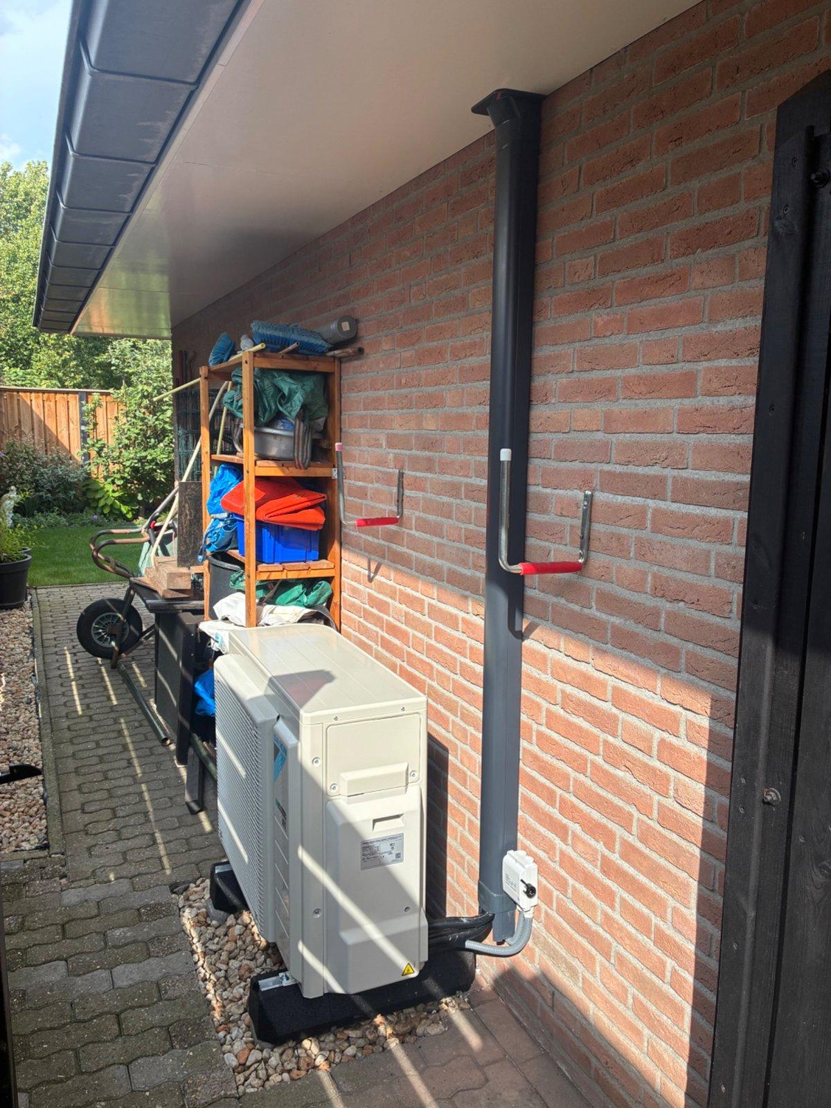 Buitenunit van de warmtepomp naast de woning in Vroomshoop