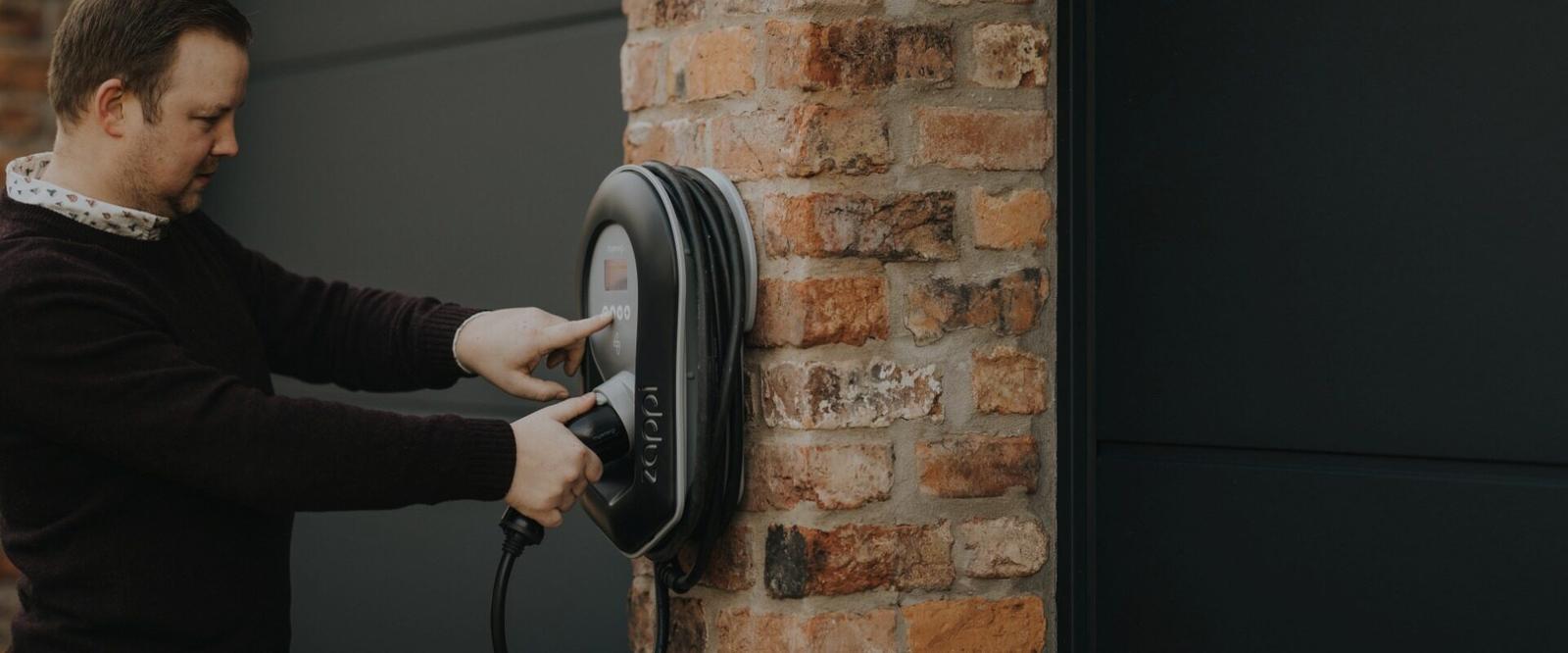 Een gebruiker sluit een elektrische auto aan op een myenergi zappi bij de woning